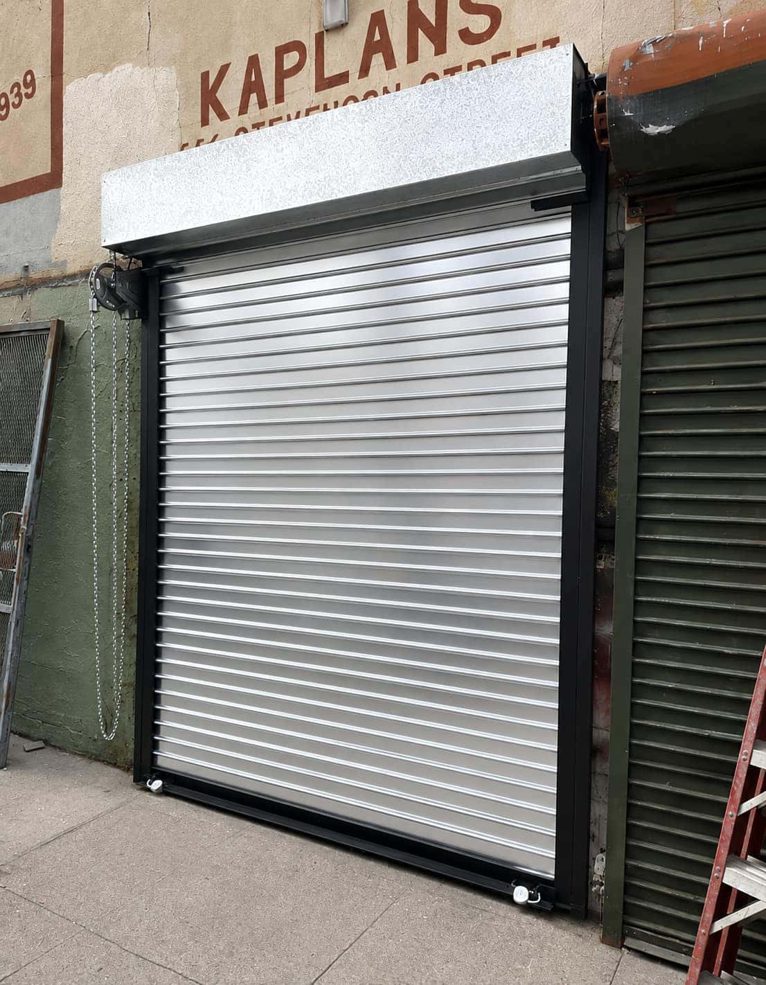 Newly installed aluminum roll up gate replacing an aged curtain on a retail storefront