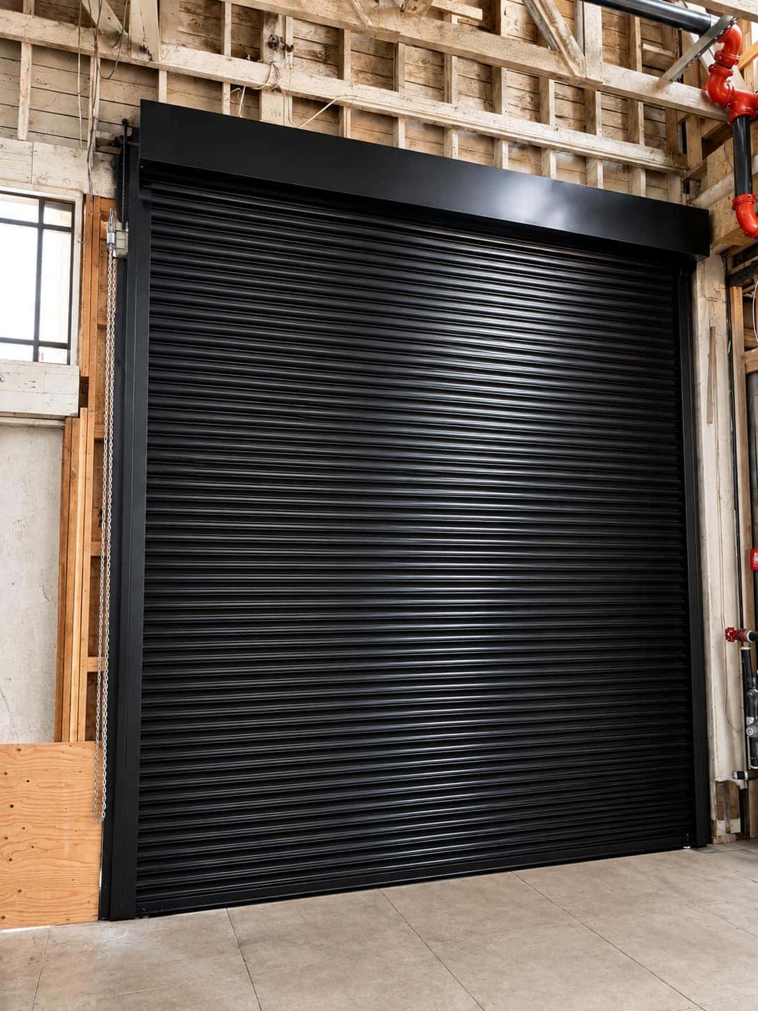 Black rolling steel service door raised inside a commercial unit during a repair visit