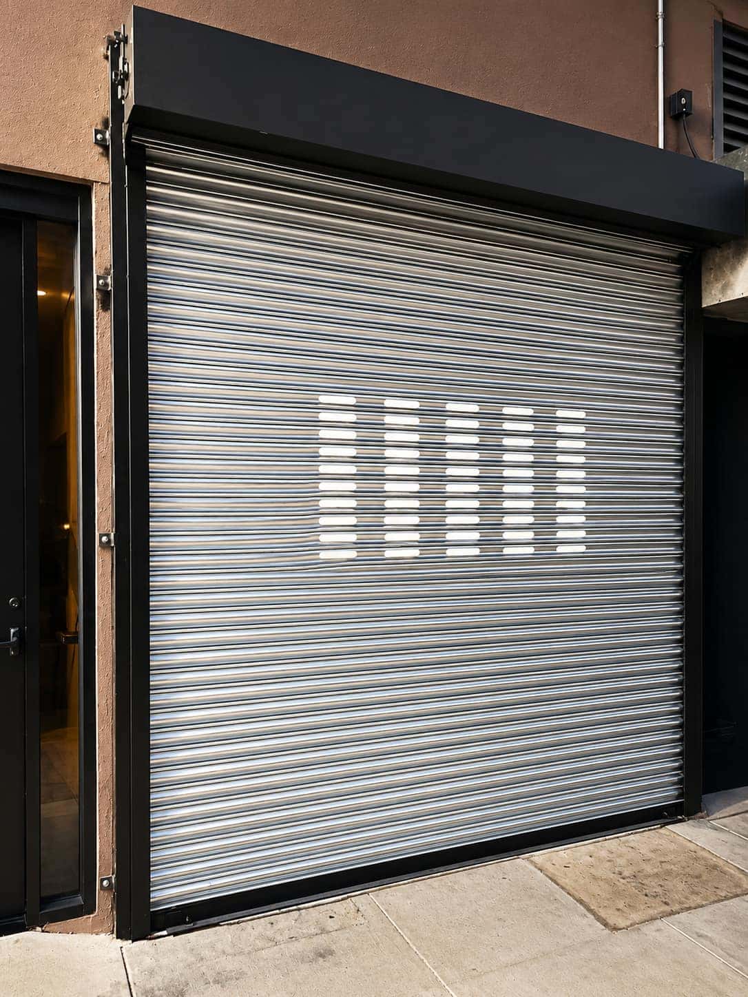 Perforated roll up security gate with vision slots closed over a storefront entrance