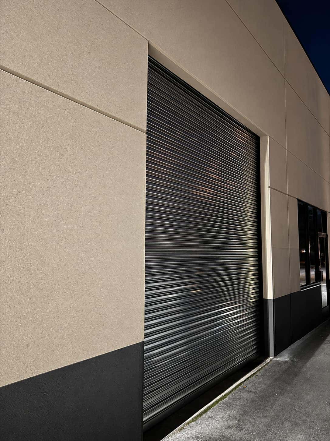 Full height black rolling steel curtain closed over a commercial building opening