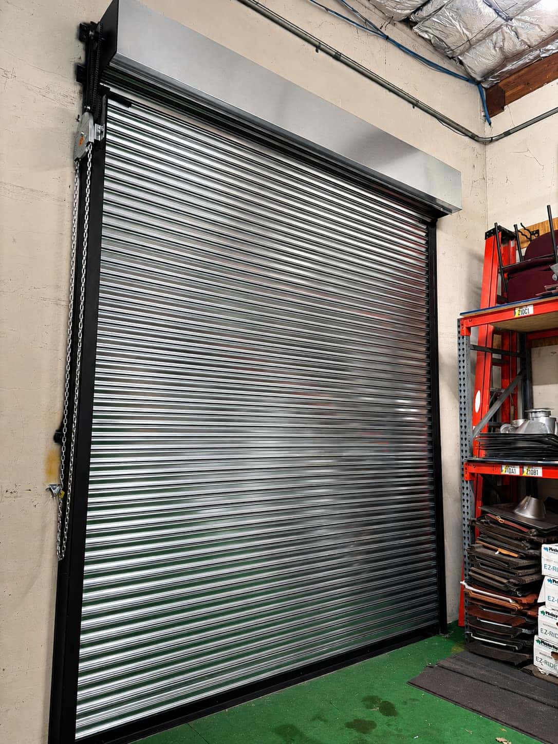 Galvanized rolling steel door with a chain hoist drive mounted inside a commercial shop
