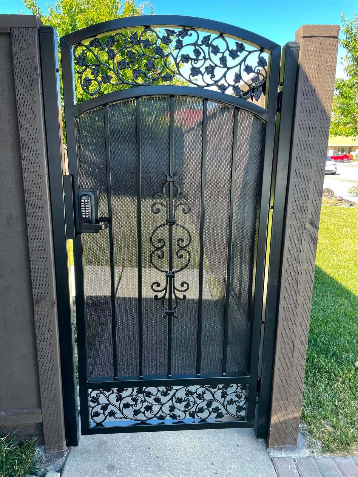Ornamental iron pedestrian gate with a keypad entry panel