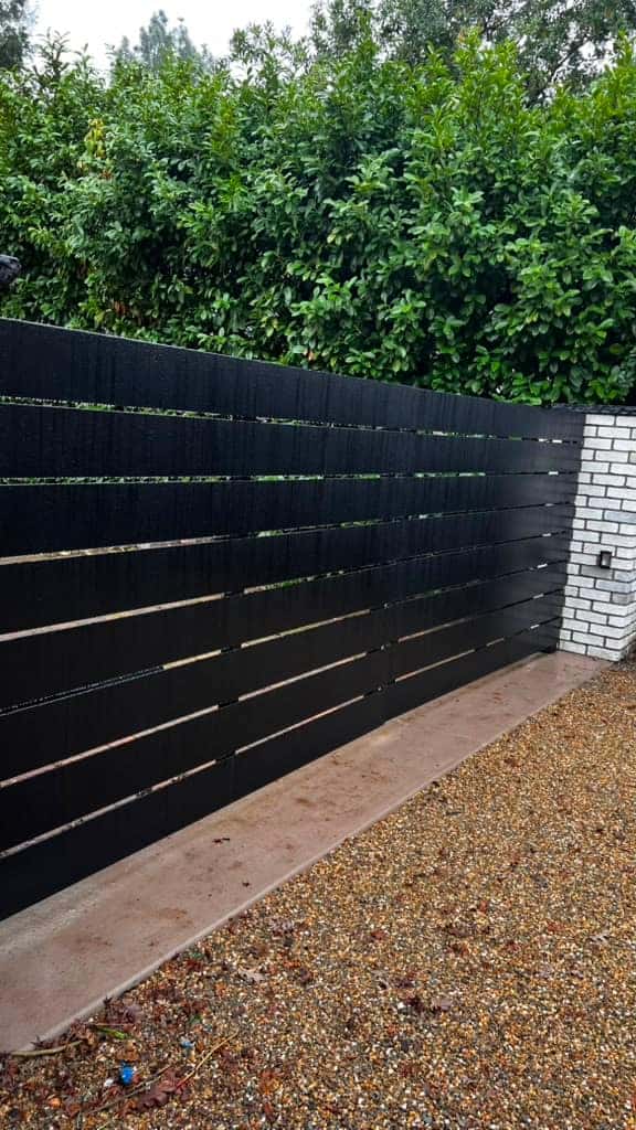 Black horizontal-slat fence line along a driveway