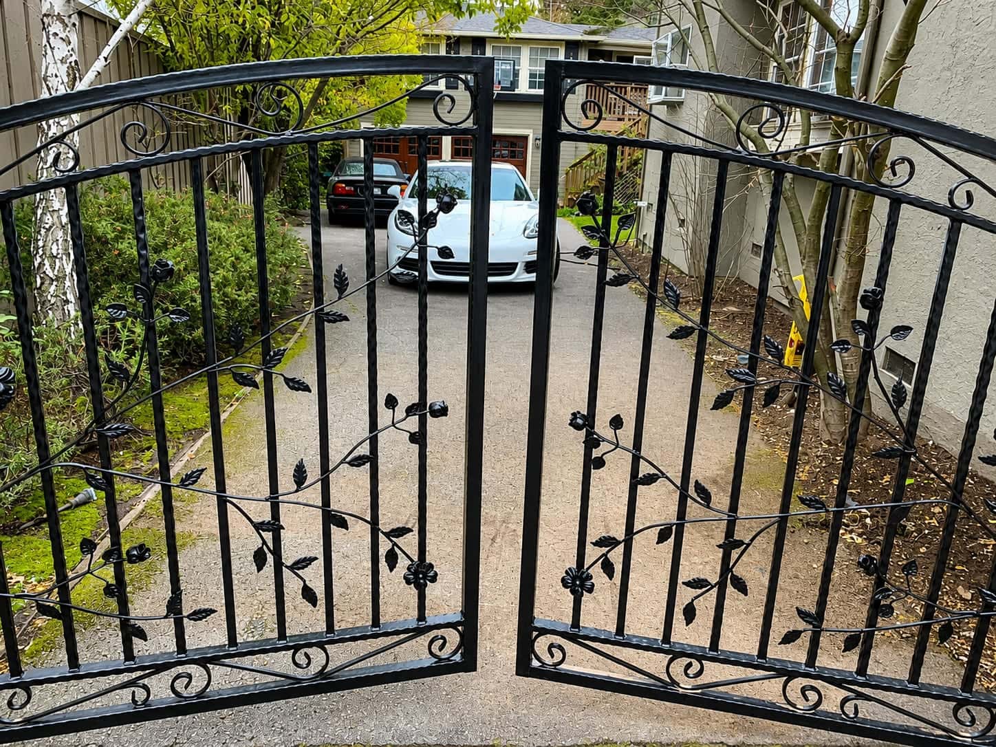 Wrought iron driveway gate with a vine motif and powder-coated finish