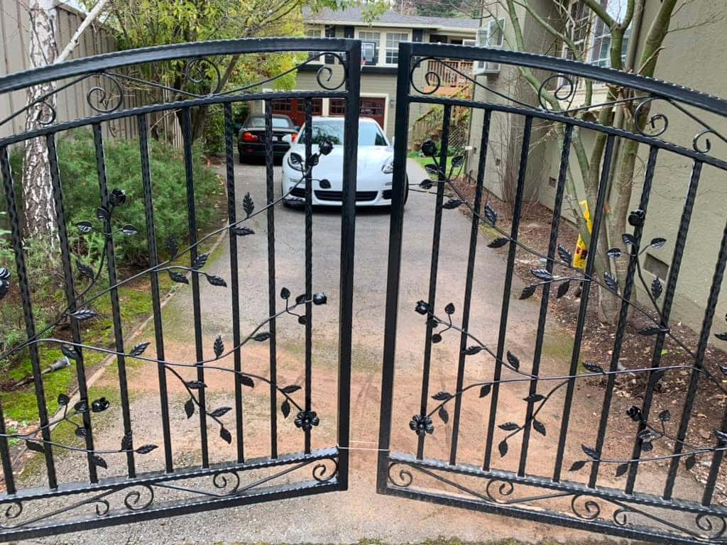 Custom ornamental iron driveway gate with vine motif installed by NGL Automatic Gates