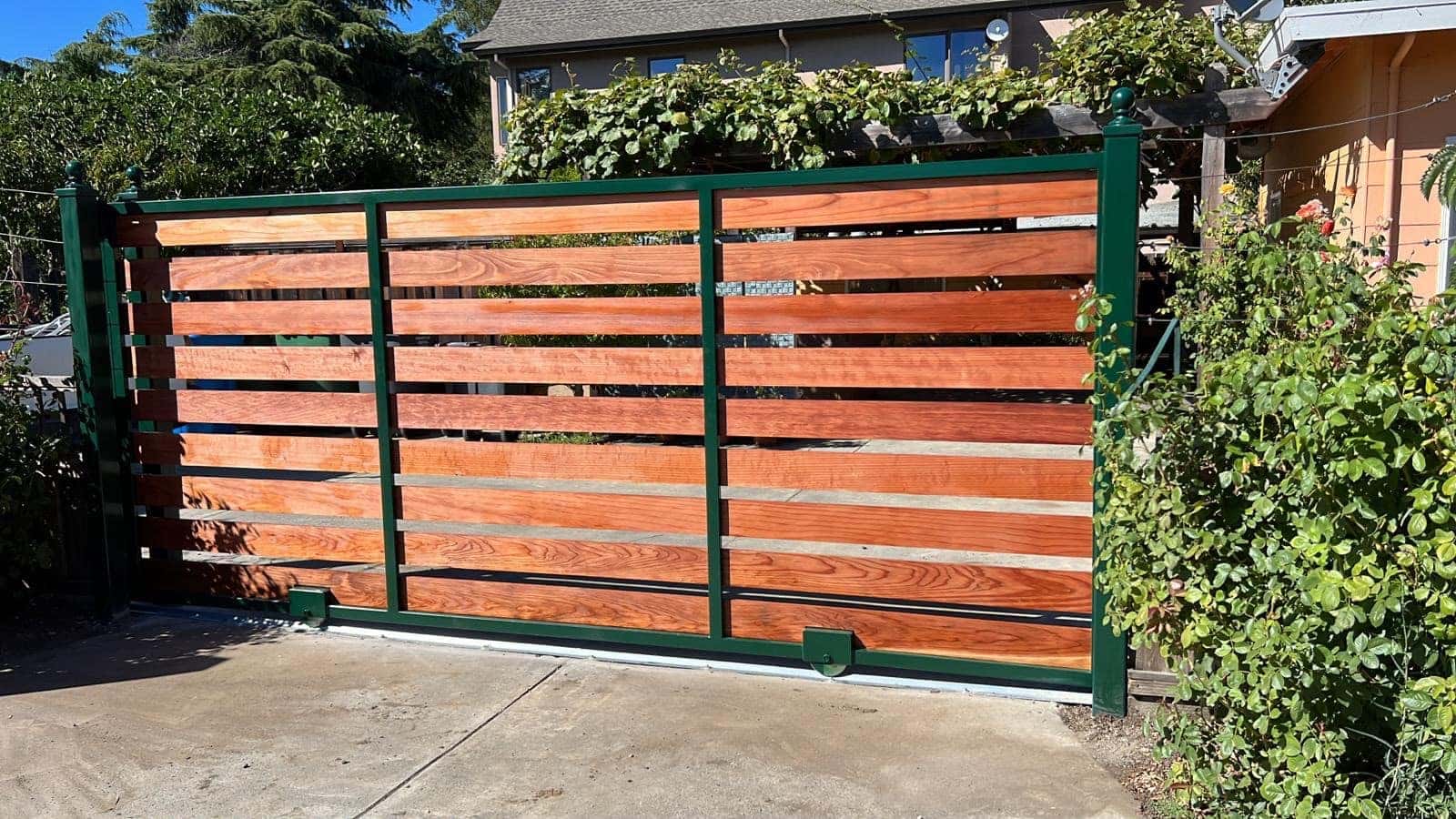 Horizontal redwood-slat driveway gate on a steel frame