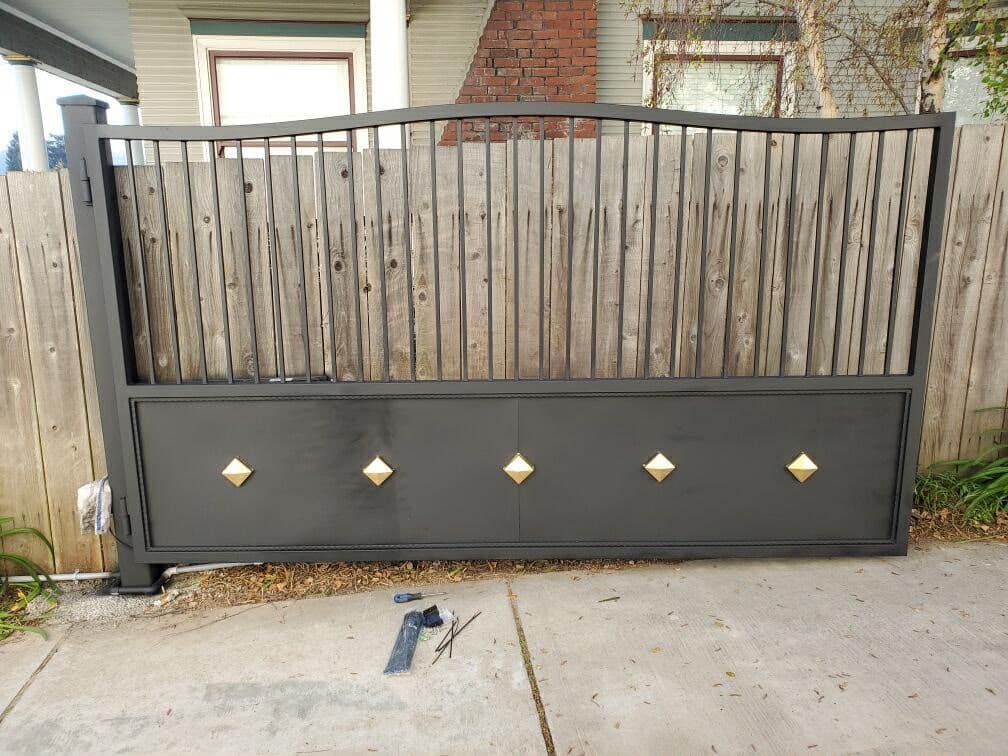 Arched wood residential driveway gate with brass diamond accents