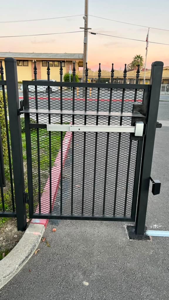 Technician realigning a gate photo-eye safety sensor during a repair